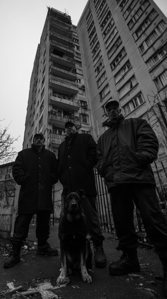 No Zone — three men and a dog in front of a tower block