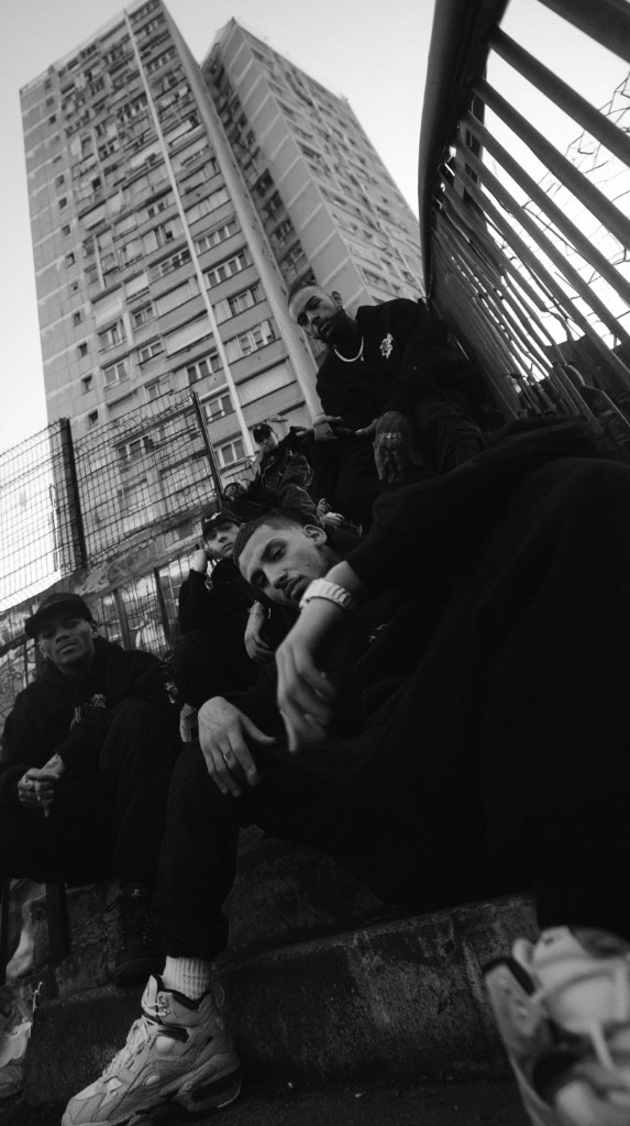 No Zone — group sitting on stairs under a tower block